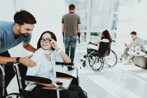 Smiling Man Hugging Girl in Wheelchair near Window