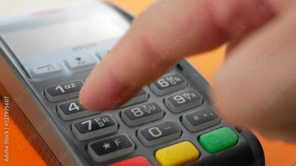 Hand of customer paying with contactless credit card with NFC technology on orange background. Credit card reader machine at bar counter with male holding credit card. Finger entering the PIN code Hand of customer paying with contactless credit card with NFC technology on orange background. Credit card reader machine at bar counter with male holding credit card. Finger entering the PIN code