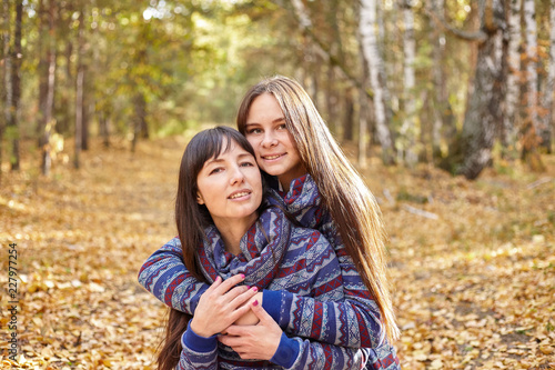 Cute portrait of mother and daughter in the autumn forest.