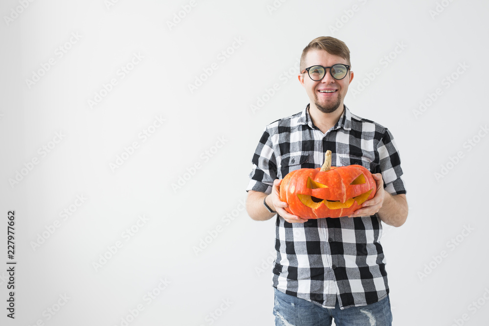 Funny handsome bearded man with carved halloween pumpkin over light background with copy space Funny handsome bearded man with carved halloween pumpkin over light background with copy space