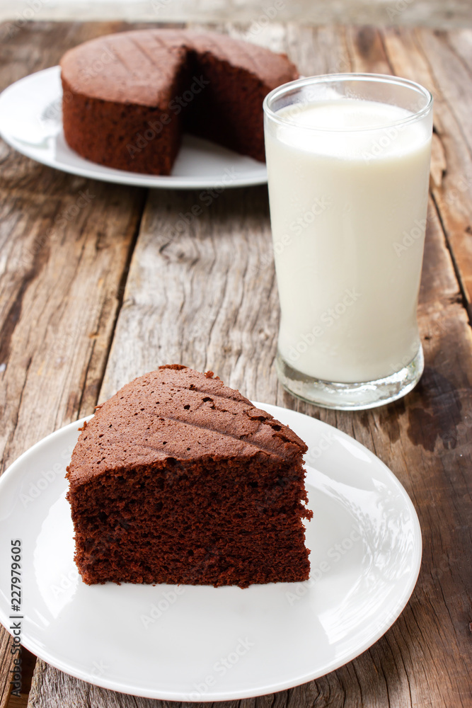 Sliced homemade chocolate cake on white served with milk. Food and drink background. Sliced homemade chocolate cake on white served with milk. Food and drink background.