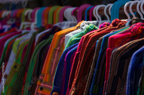 Clothes on hangers on street market stand. Traditional Peruvian fabric pants, sweaters. Colorful variety, fashion style, bargain, sales concepts