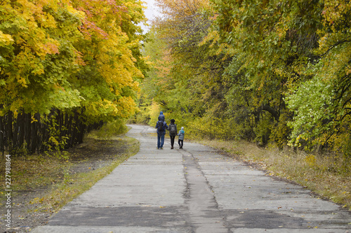 Family with two sons are walking in the autumn park. Back view