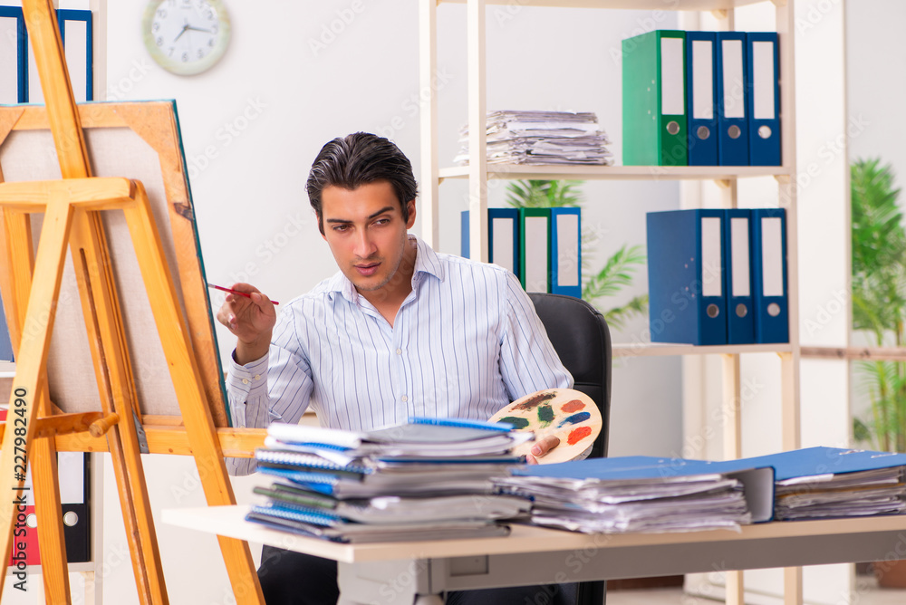 Young handsome employee enjoying painting at the office Young handsome employee enjoying painting at the office
