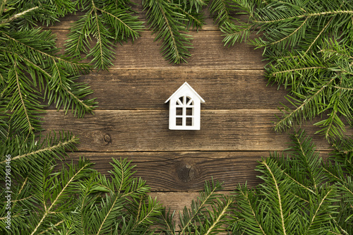 Small white house on wooden  background. Frame of fir branches © somemeans