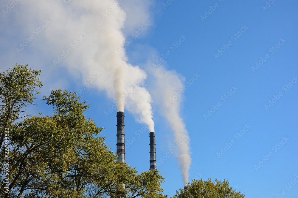 Smoking chimneys against the blue sky. Environmental pollution, ecological problems.