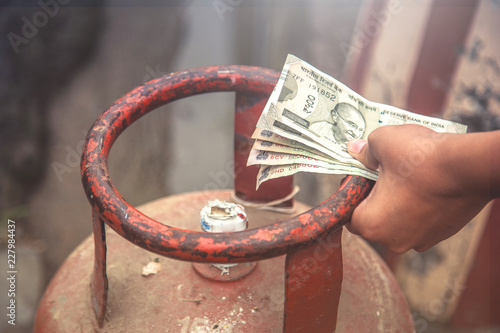 Photography Man holding LPG gas cylinder and Indian rupee notes