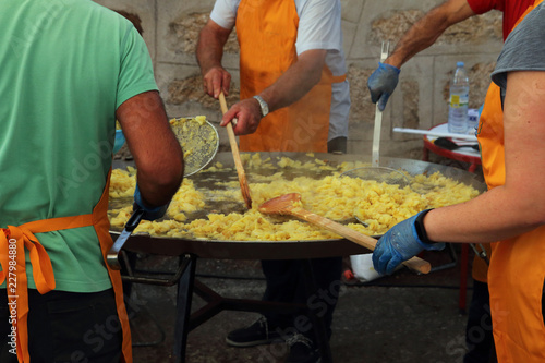 Photography gente removiendo las patatas en una sartén gigante para preparar una tortilla es