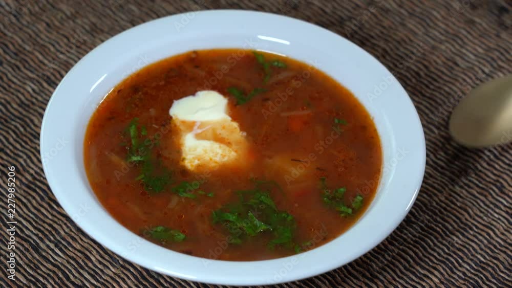 White plate with a homemade appetizing and tasty borsch. Red beetroot vegetable soup. Ukrainian and russian traditional red beet soup - borscht or borsch, close up White plate with a homemade appetizing and tasty borsch. Red beetroot vegetable soup. Ukrainian and russian traditional red beet soup - borscht or borsch, close up