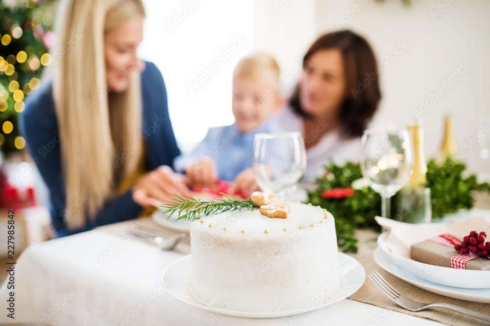 A white a cake on table set for dinner at Christmas time.