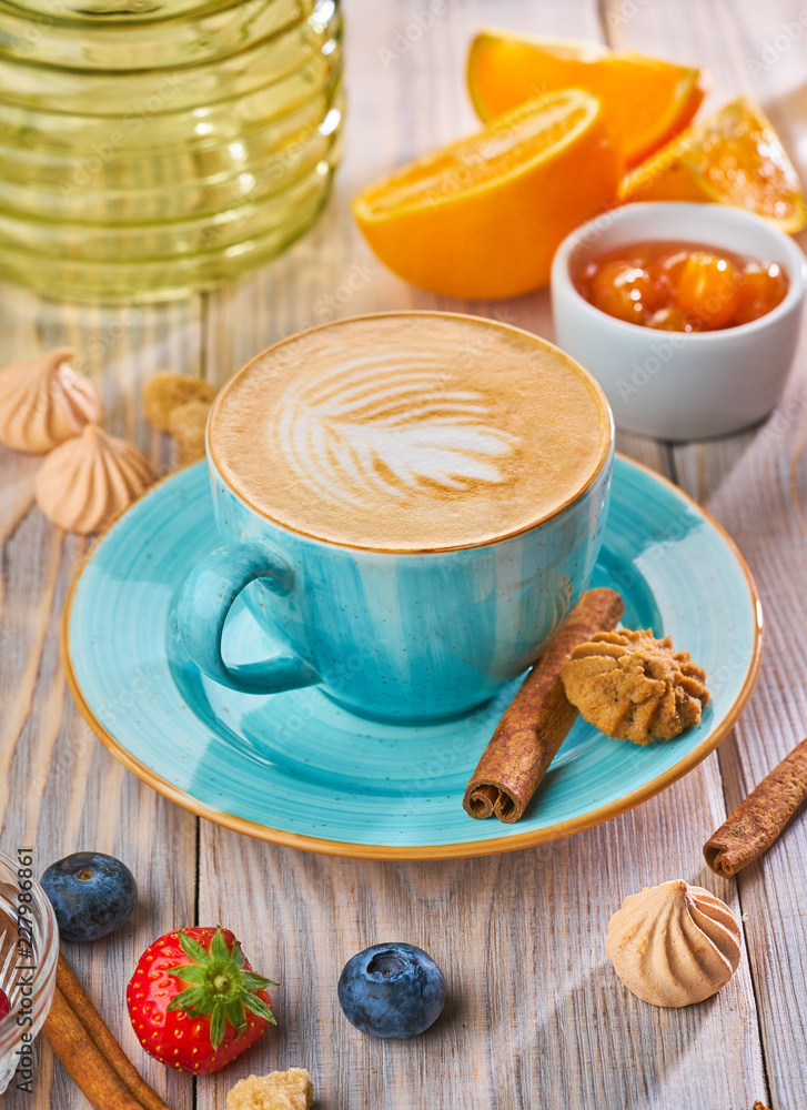 Cappuccino in a blue cup with biscuit cookies on a rustic wooden table Cappuccino in a blue cup with biscuit cookies on a rustic wooden table