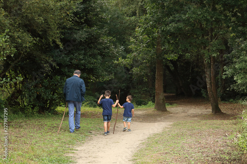 abuelo y nietos de espaldas caminado por un sendero en el monte