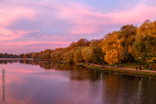 Autumn landscape. Fantastic dramatic colorful flaming sky, trees and reflections in the lake after sunset in the park. Calm and tranquility. Autumn in Moscow parks, Russia.
