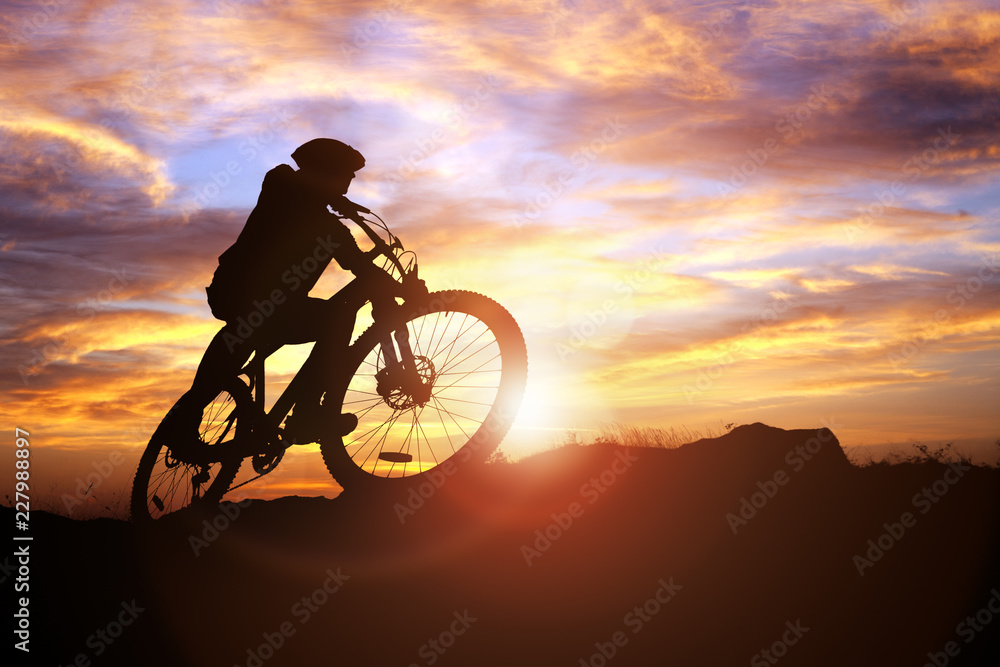 Obraz premium Mountain biker silhouette in action against the sunset concept for sport and exercise