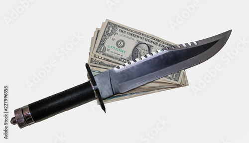 large hunting knife with rope handle and serrated face over a pile of dollars.