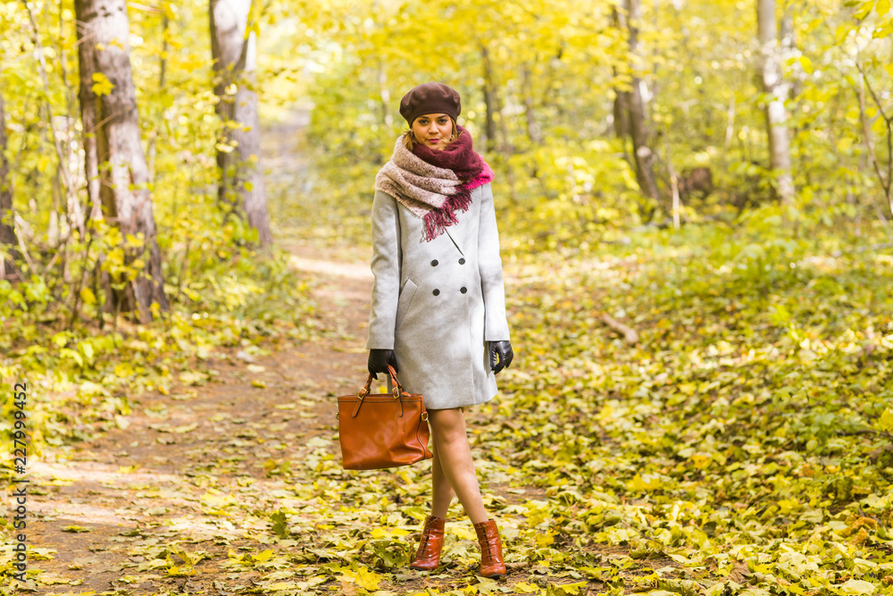 Season, nature and people concept - woman in autumn park posing with bag Season, nature and people concept - woman in autumn park posing with bag