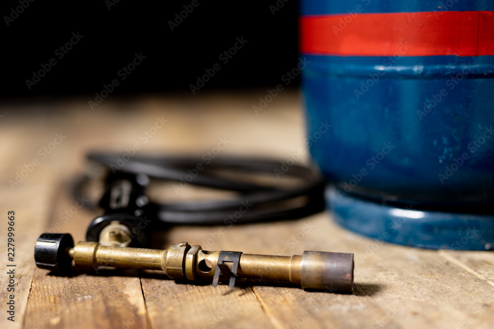 An old gas burner for industry. Accessories for a mechanic on an old wooden table. Dark background.
