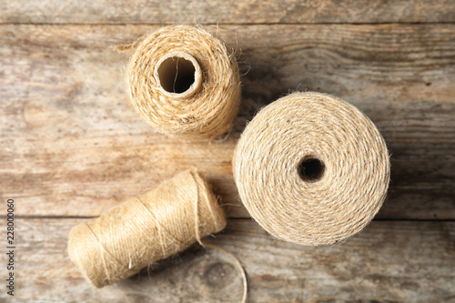 Natural hemp rope spools on wooden background, flat lay