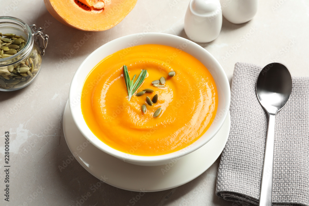Bowl with tasty pumpkin soup served on gray table Bowl with tasty pumpkin soup served on gray table