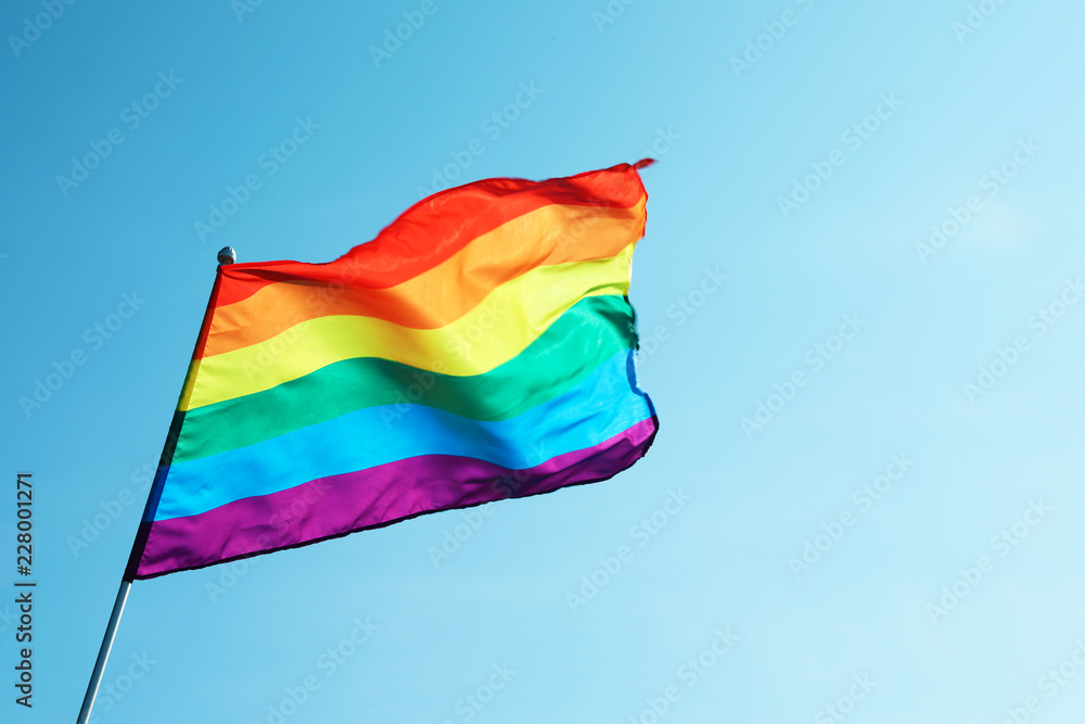 Rainbow gay flag against blue sky, space for text. LGBT concept Rainbow gay flag against blue sky, space for text. LGBT concept