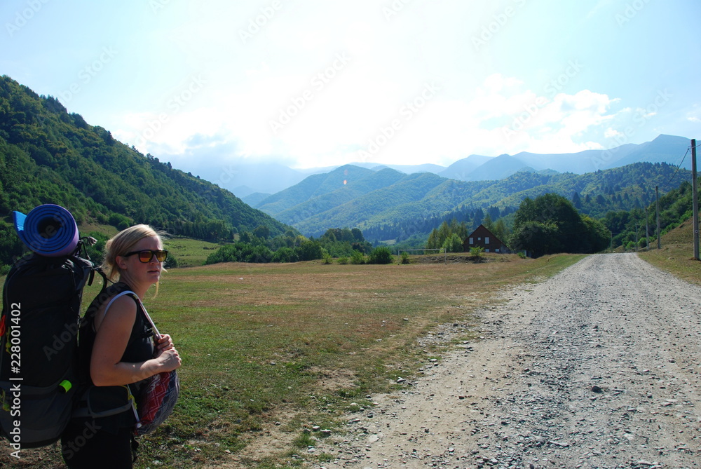 A woman with backpack hiking into Carpathian Mountains, view nature of Transylvania, Romania
