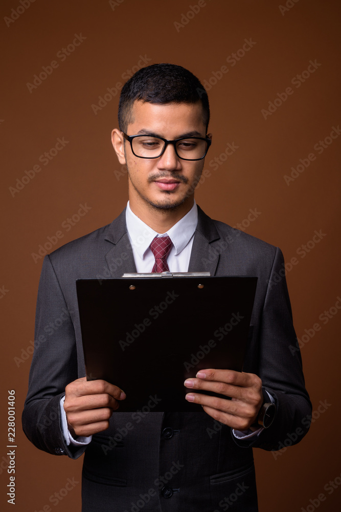 Young multi-ethnic Asian businessman against brown background