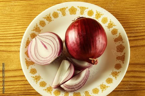 Red whole and cut onion isolated on wooden background top view