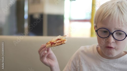 Handsome boy eats pizza. A little albino boy is eating a margarita pizza. Close-up of a boy with a slice of margarita pizza