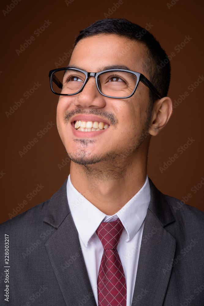 Young multi-ethnic Asian businessman against brown background Young multi-ethnic Asian businessman against brown background