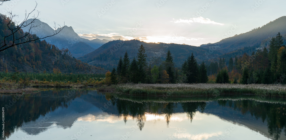 Naklejka premium Almsee bei Sonnenuntergang mit bunten Laubbäumen und Herbstblättern, an einem wunderschönen Herbsttag