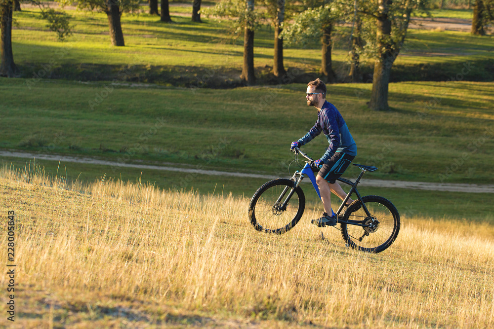 A cyclist rides the hills, Beautiful portrait of a guy on a blue bicycle A cyclist rides the hills, Beautiful portrait of a guy on a blue bicycle