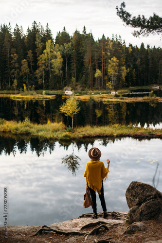 Woman in a yellow poncho and hat in the autumn time in national park Nuuksio, Finland