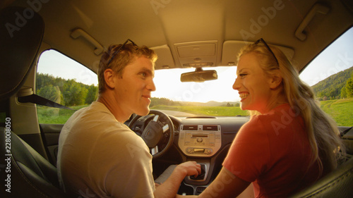 CLOSE UP: Happy woman and man looking into each other's eyes while driving. © helivideo