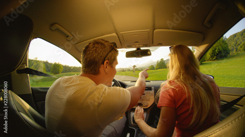 CLOSE UP: Young man pointing where the couple will drive during their road trip.