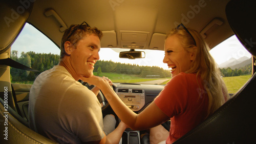 CLOSE UP: Woman laughs after kissing boyfriend driving them on sunny evening. © helivideo