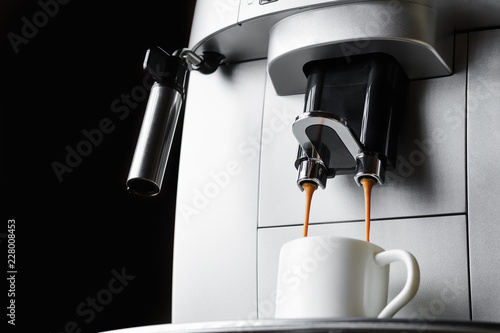 Modern coffee machine brews espresso coffee in white cup