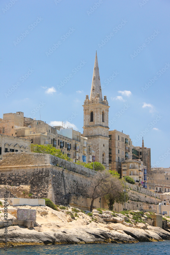Valletta Grand Harbor the most famous view with spire of bell tower of St. Paul's Anglican Pro-Cathedral church in sunny day from the water