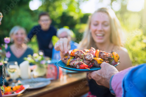 cheerful family gathered around a table for a bbq in the garden