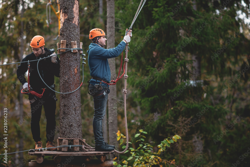 Foto de Hiking in the rope park two young people. two man in a helmet ...