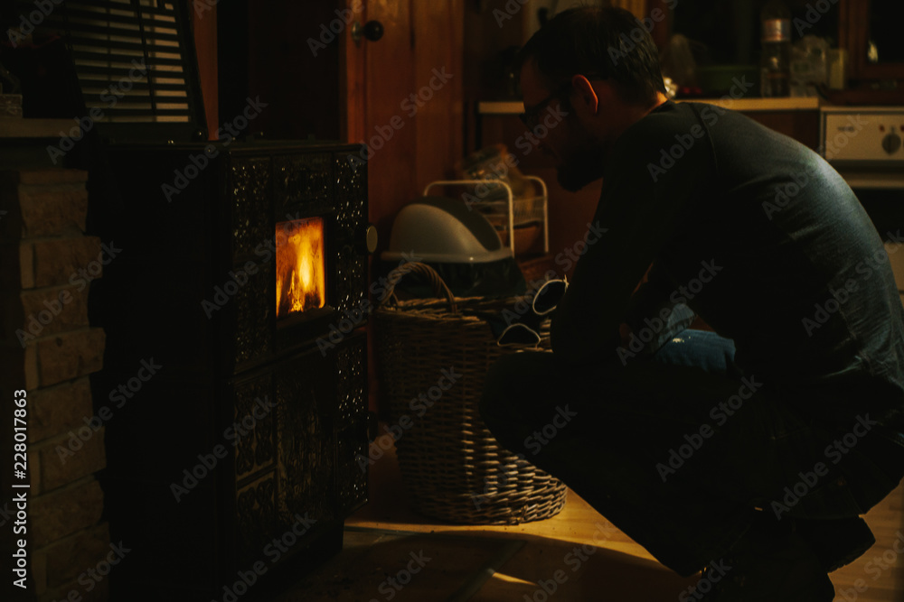 man sitting in front of an oven while watching the flames man sitting in front of an oven while watching the flames