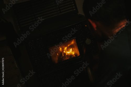 man in front of an oven drinking a beer and watching the flames