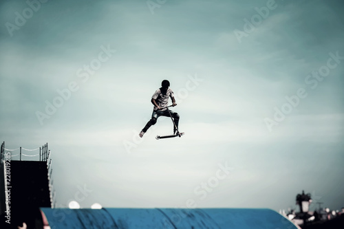 Bild auf Leinwand Extreme sport, contrast silhouette of young man, young man doing jump with scoot