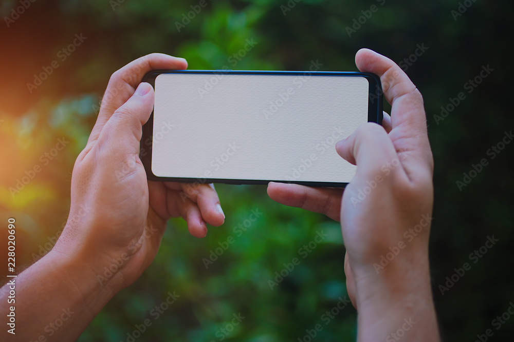 Two hands holding modern smartphone with blank screen for your text message or content, man's hand using cellphone with empty display Two hands holding modern smartphone with blank screen for your text message or content, man's hand using cellphone with empty display