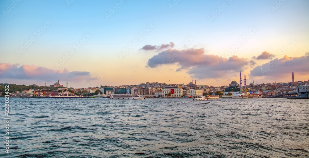 Touristic landmarks from sea voyage on Bosphorus. Cityscape of Istanbul at sunset - old mosque and turkish steamboats, view on Golden Horn.