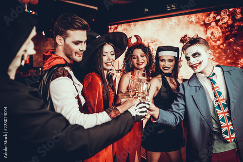 Young People in Halloween Costumes Clinking Glasses