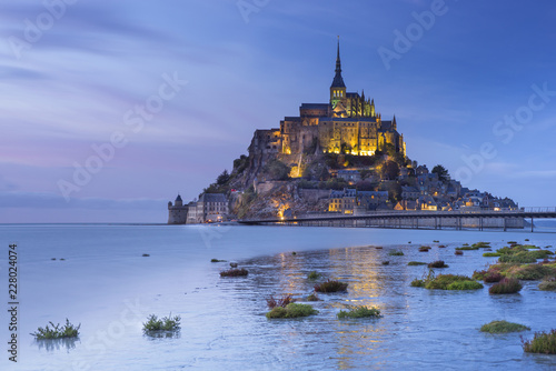 low tide on the coast and view to the castle with night lights in Normandy in France