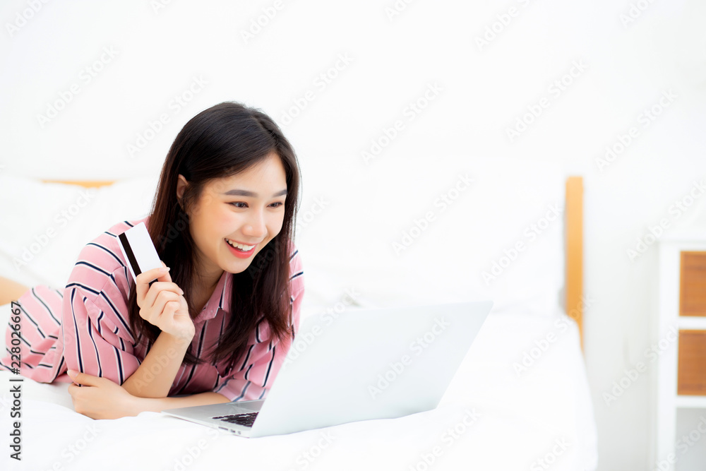 Beautiful of portrait young asian woman lying users credit card with laptop, content girl shopping online and payment with notebook computer on bed at bedroom, lifestyle concept. Beautiful of portrait young asian woman lying users credit card with laptop, content girl shopping online and payment with notebook computer on bed at bedroom, lifestyle concept.