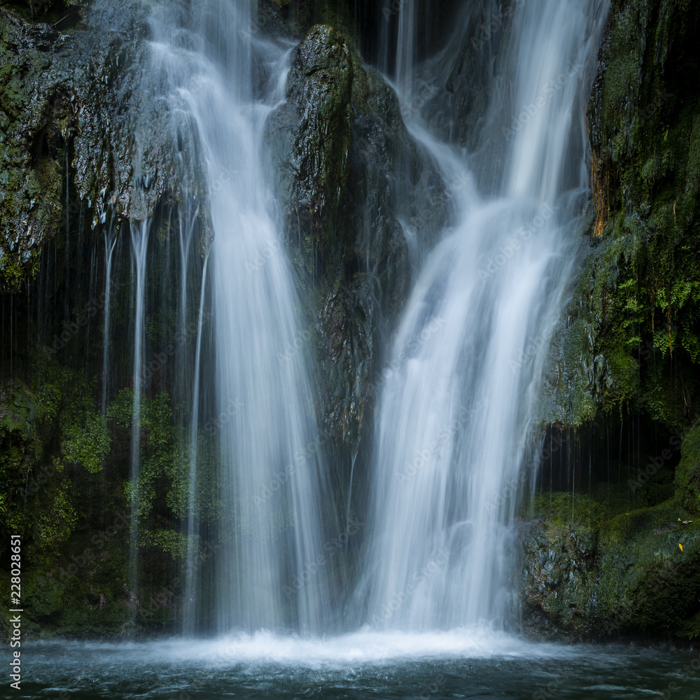 Waterfall flowing on rock in woods in long exposure Waterfall flowing on rock in woods in long exposure