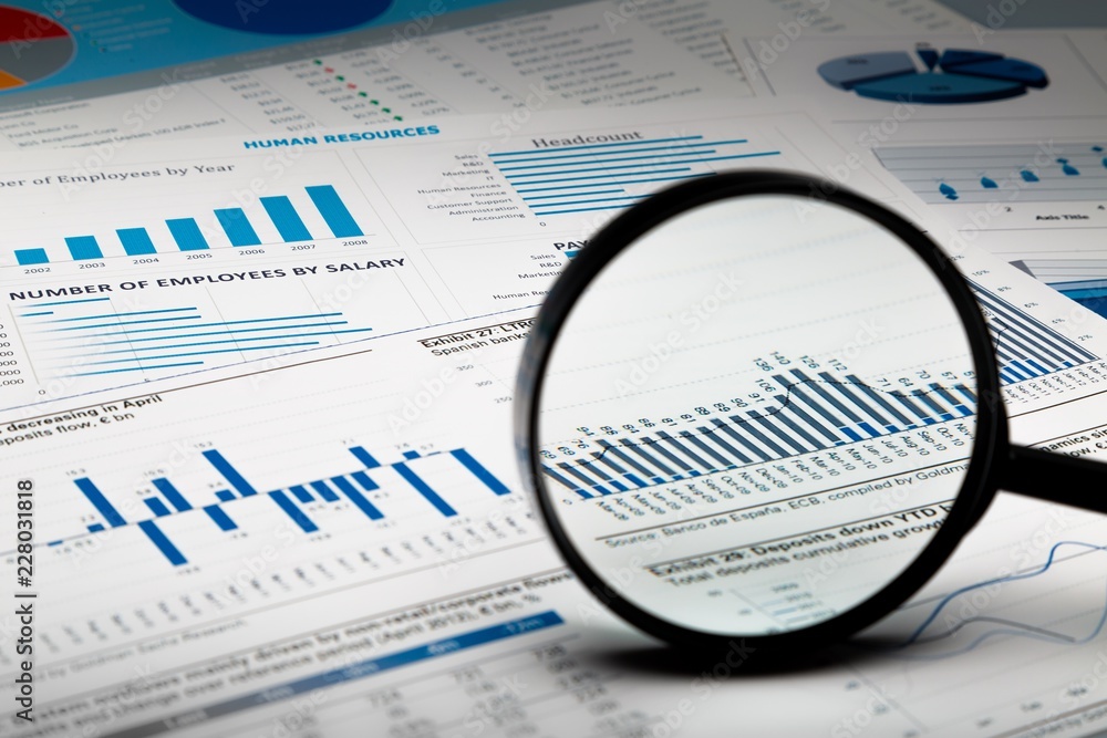 Magnifying Glass on Business Graphs and Charts Magnifying Glass on Business Graphs and Charts