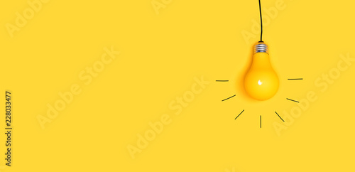 One hanging light bulb on a yellow background